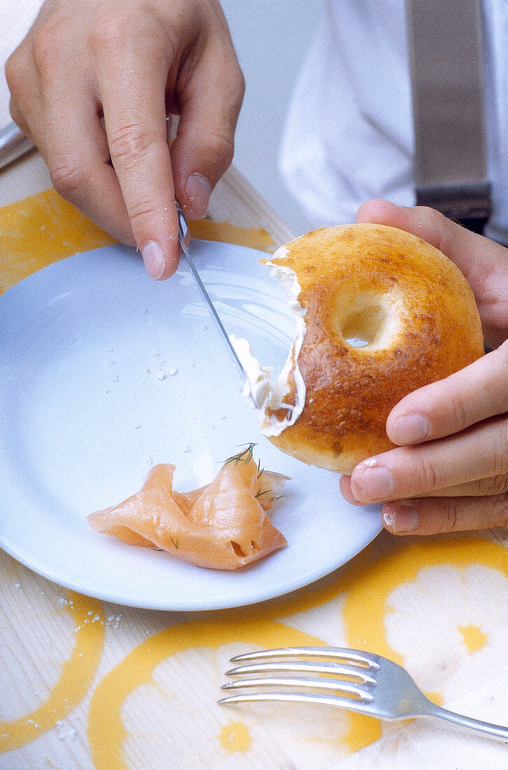 Close-up of hand applying butter on bagel