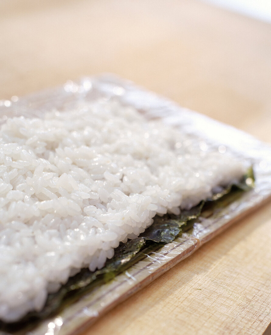 Step: Für California Uramaki werden auf eine Matte Nori und Reis gelegt