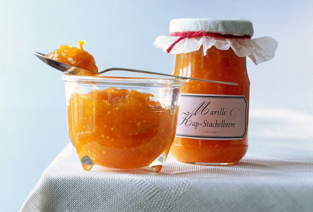 Close-up of apricot and cape gooseberries sauce in glass jars on table