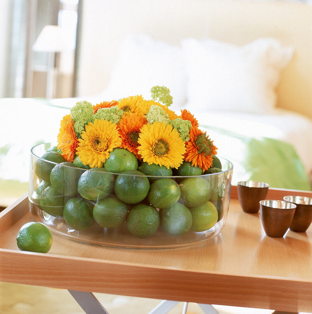 Ringelblumen und Limonen in einer großen Glasschale arrangiert