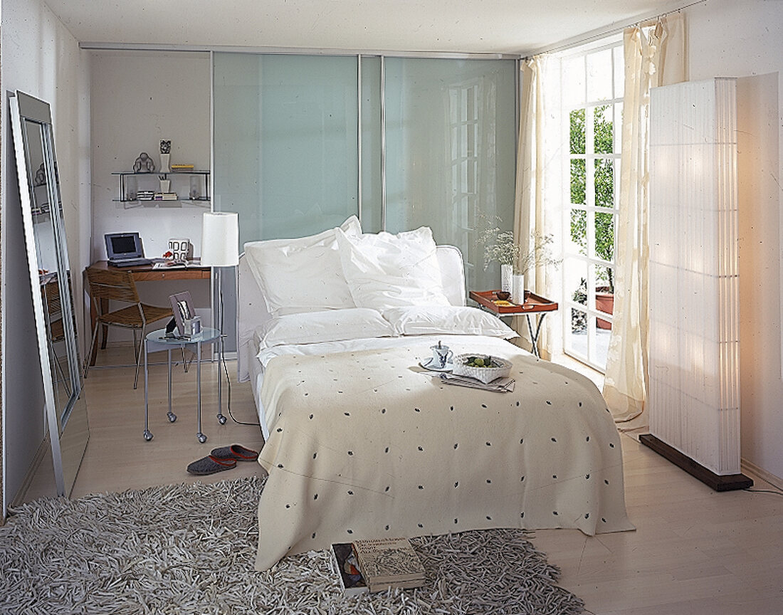 Elegant kühles Schlafzimmer mit Arbeitsplatz hinter Glasschiebetür