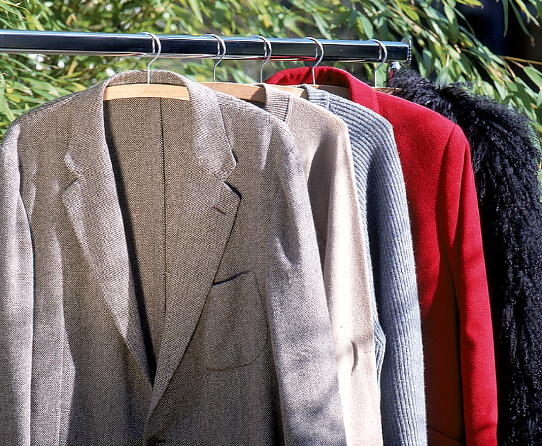 Mehrere Jacken hängen auf einer Kleiderstange.