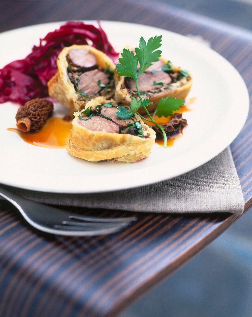 Hare fillets in crispy puff pastry with spiced red cabbage on plate