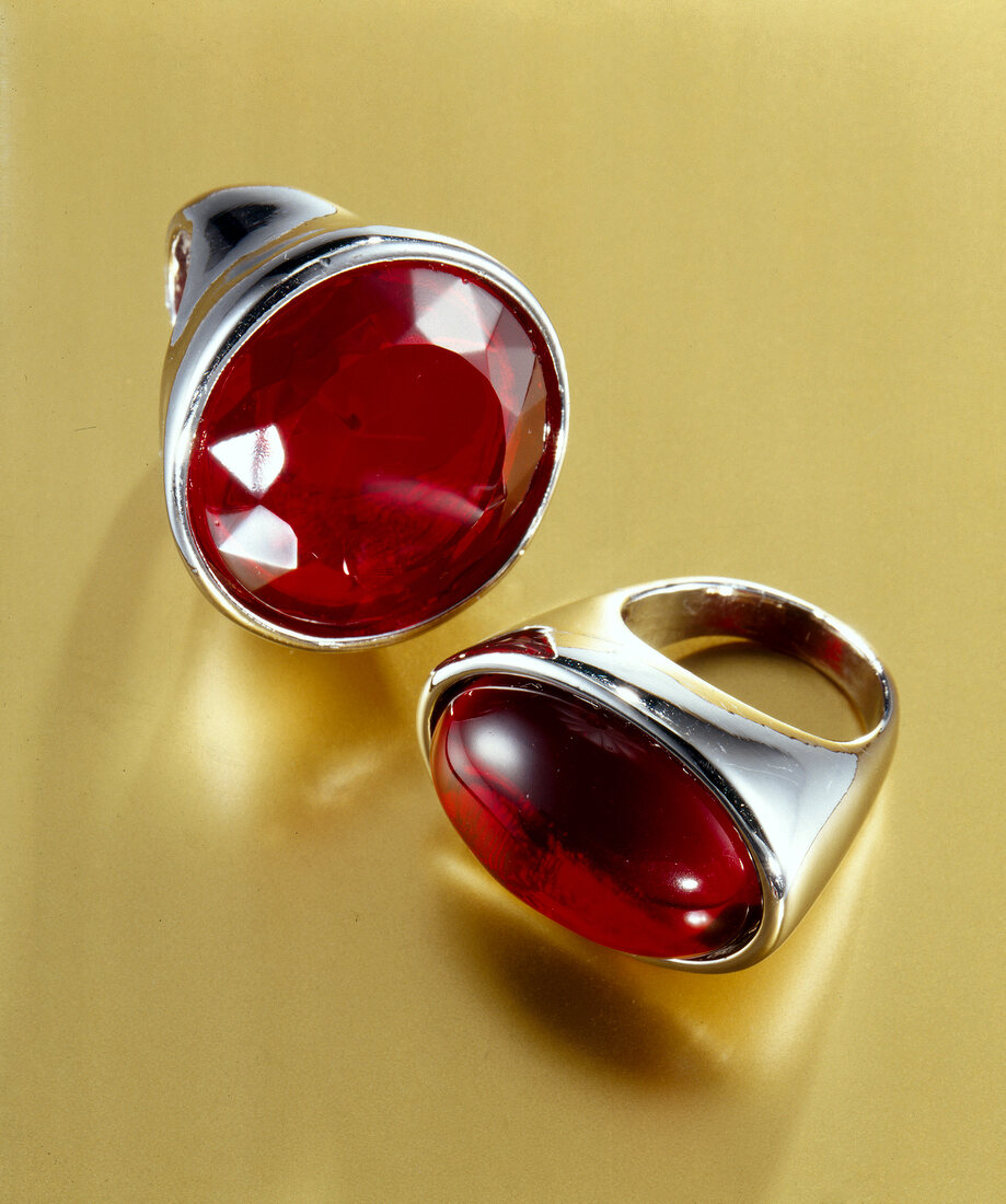 Close-up of silver plated round and oval ring with red stones