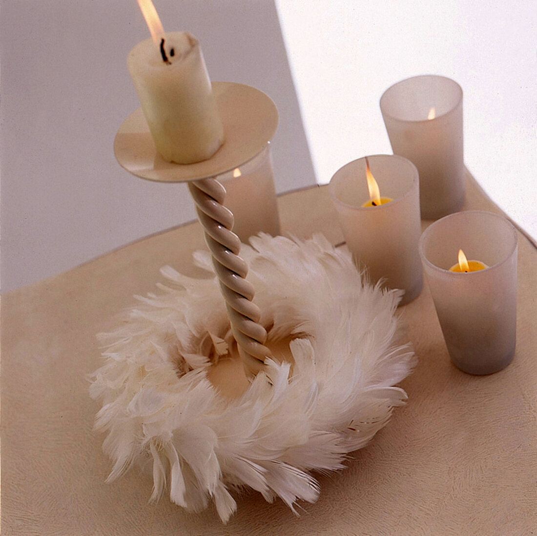 Kerzenständer mit einem  weißen Federkranz,daneben kl. Windlichter