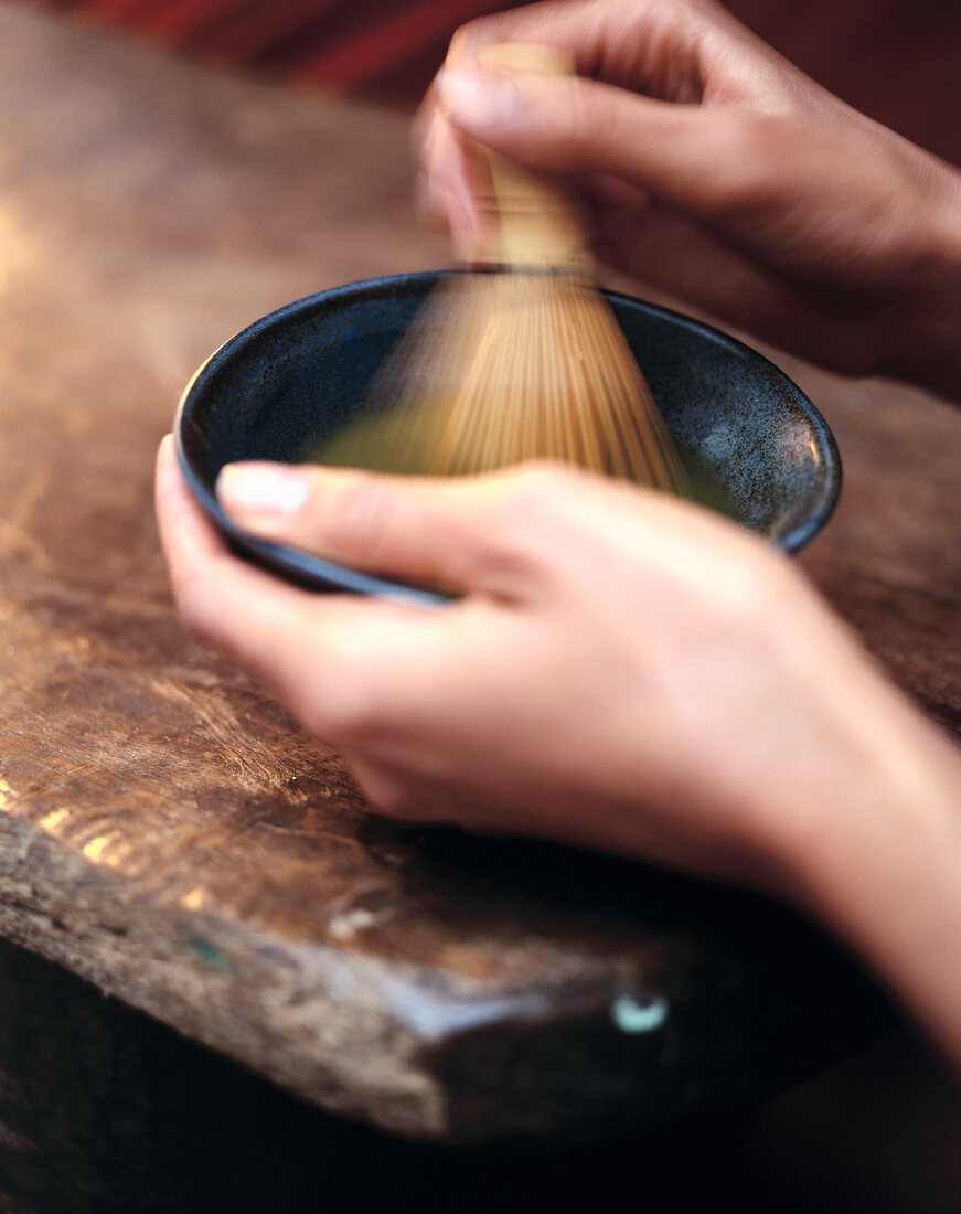 Tea powder being stirred with bamboo brush in bowl
