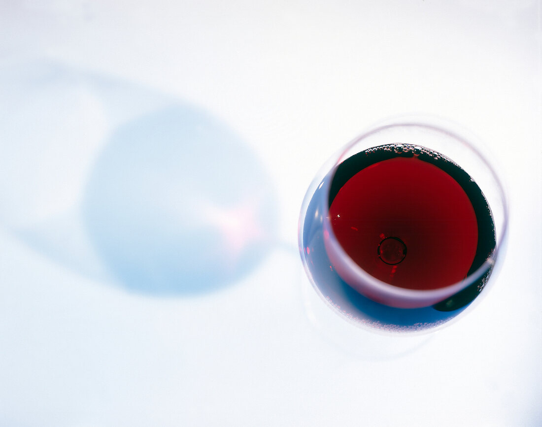 Glass of red wine on white background, overhead view