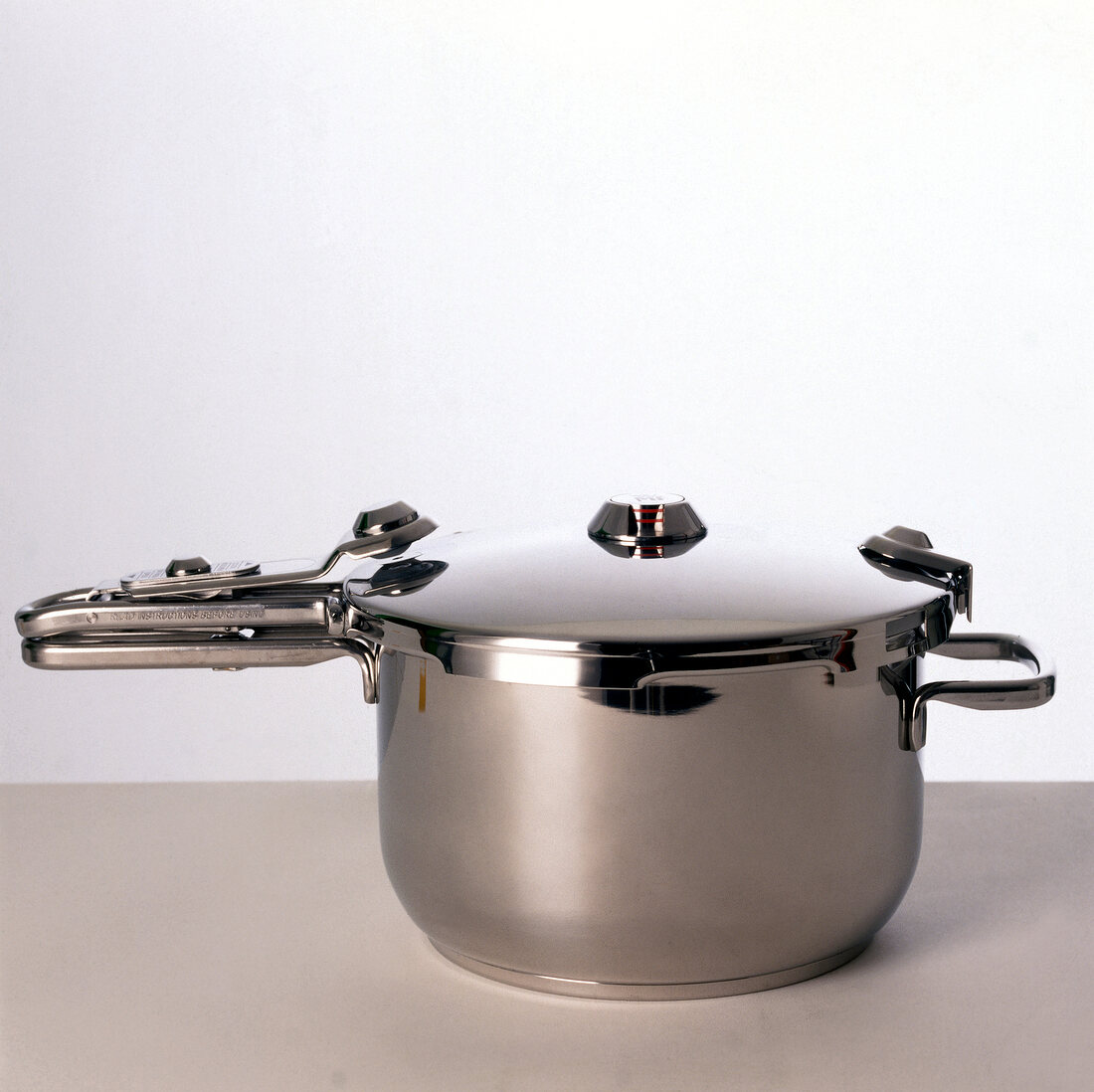 Stainless steel pressure cooker on gray surface