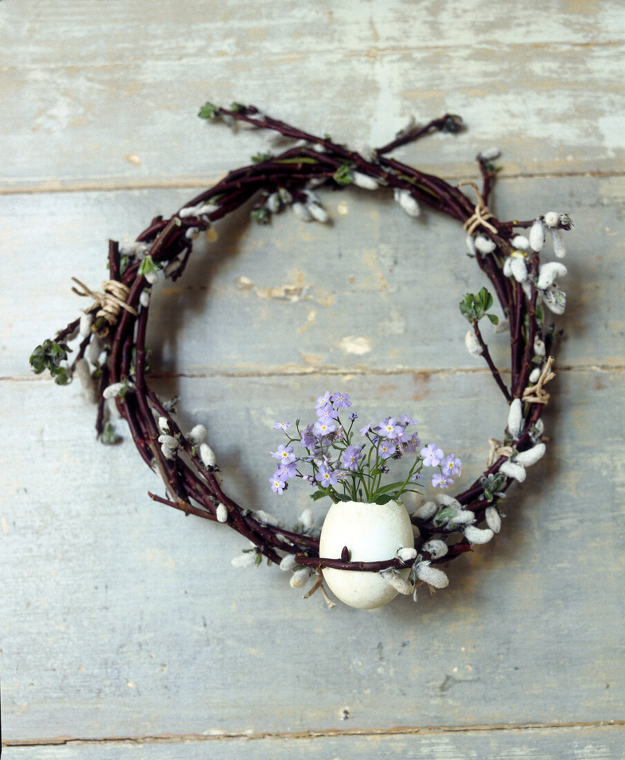 Egg shell with flowers on branch of pussy willow on wood