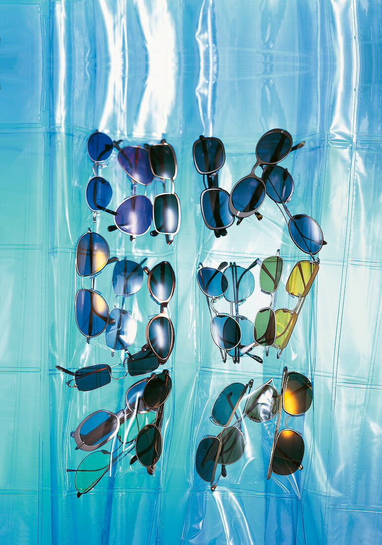 Viele Sonnenbrillen auf blauer Plastikfolie liegend