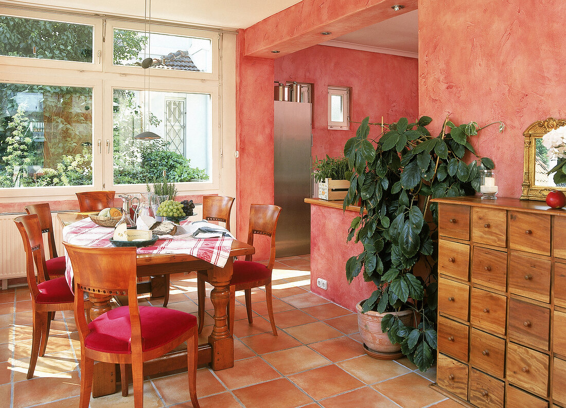 Eßplatz in warmen Farben, rote Wände Cotto-Fliesen, schwerer Holztisch