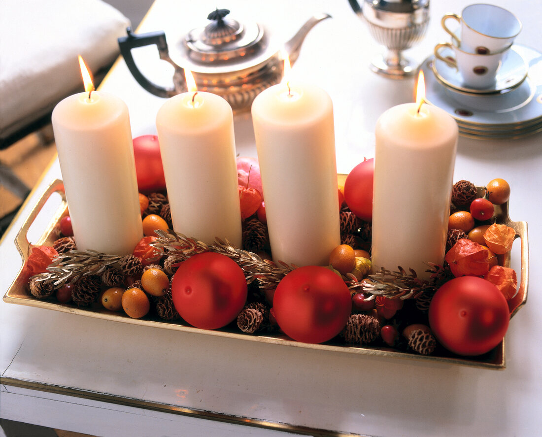 4 dicke weiße Kerzen m. Tannenzwei- gen+Früchten auf Goldenem Tablett.
