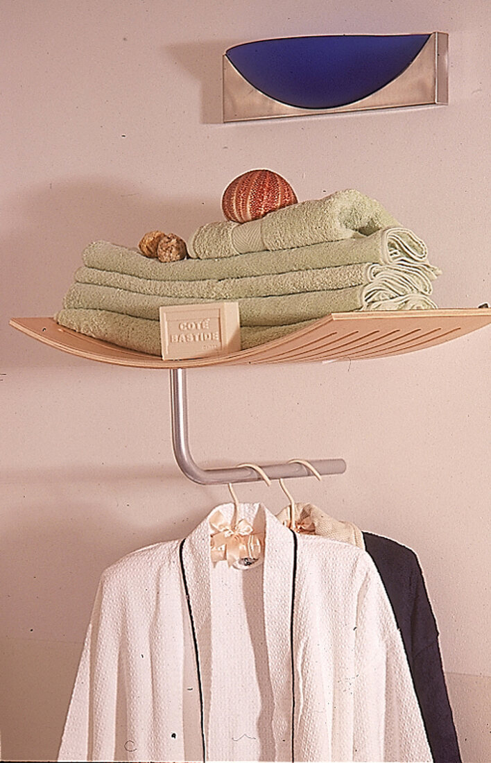 Holzablage mit  Handtücher,darunter hängen zwei Bademäntel.X