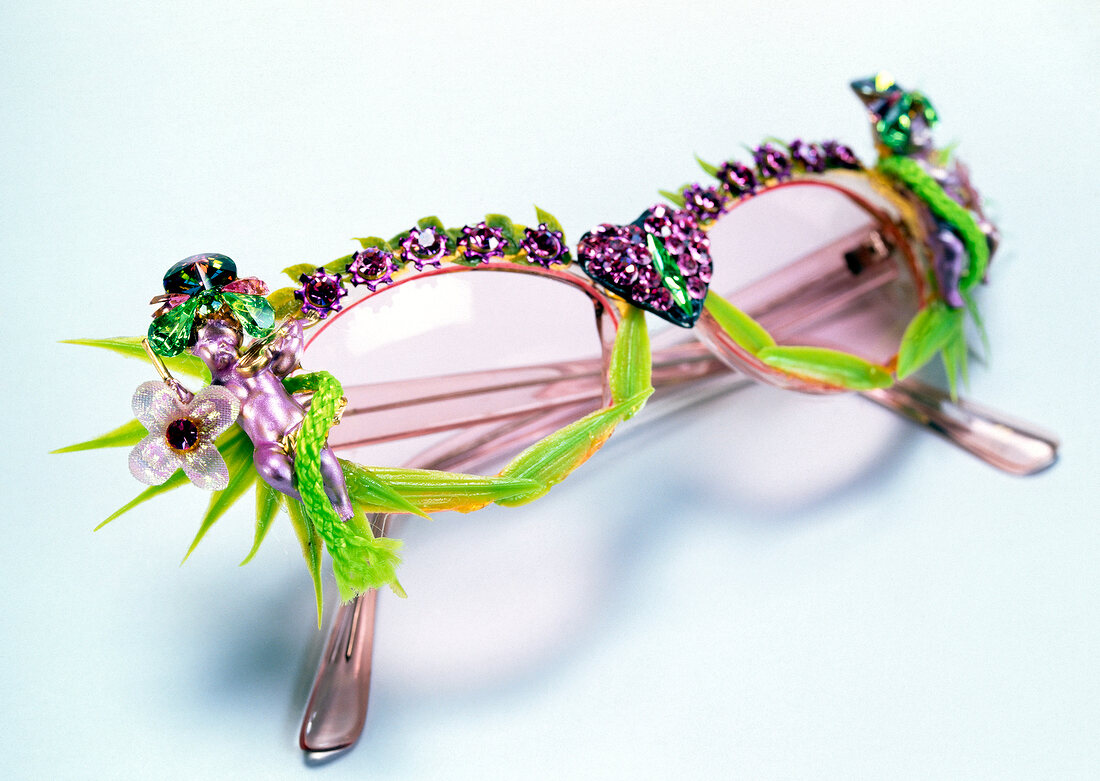 Close-up of pink sunglasses with heart shaped of rhinestones on white background