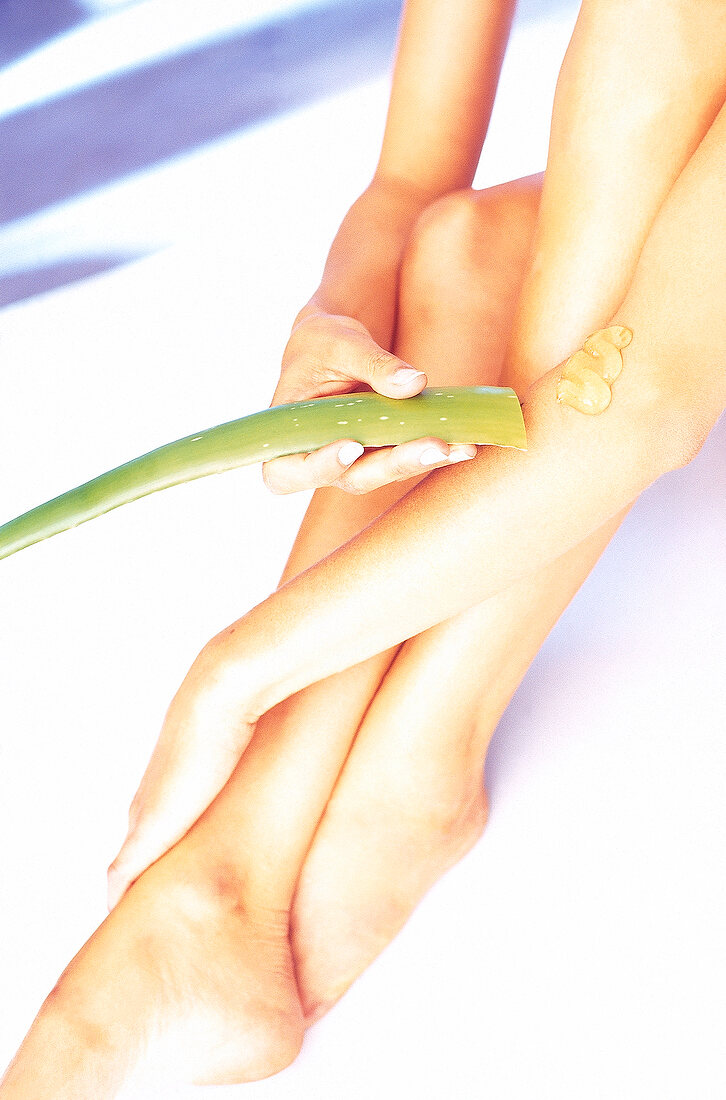 Nackte, sitzende Frau hält ein Aloe- blatt in der Hand