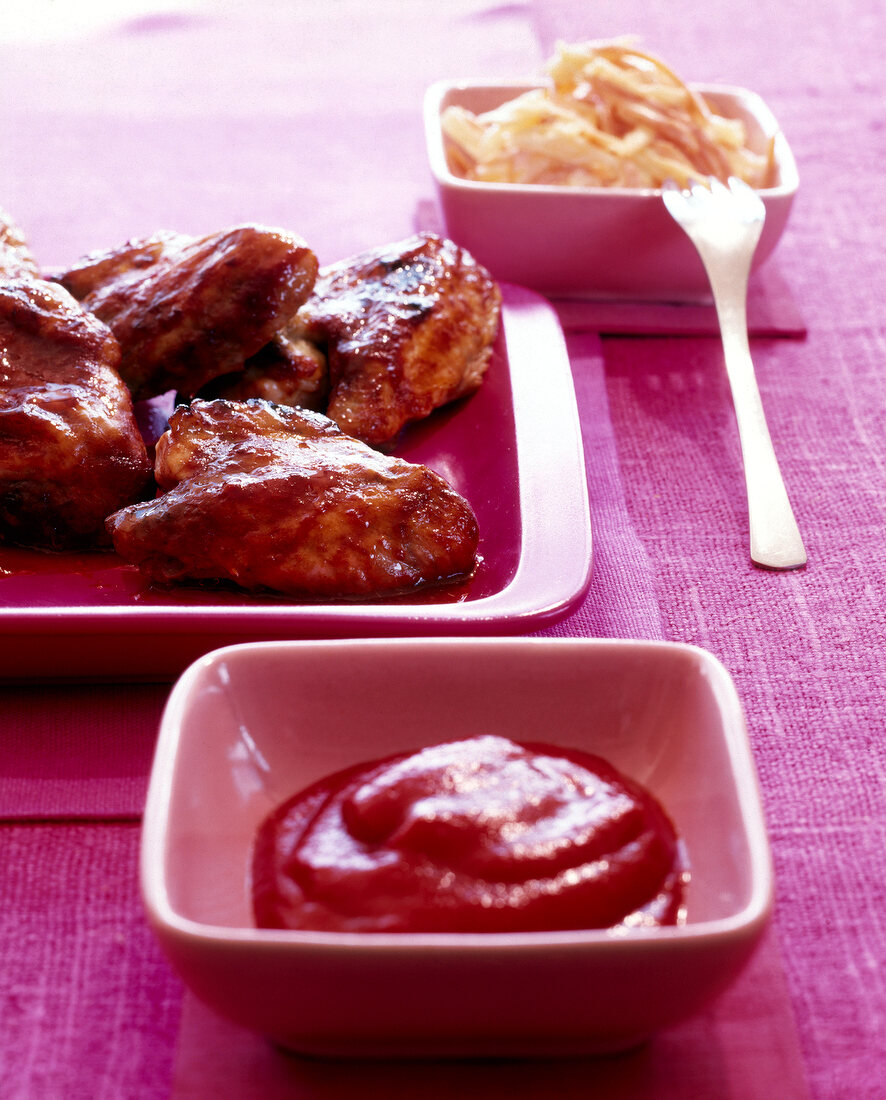 Close-up of barbecued chicken wings on plate with tomato sauce