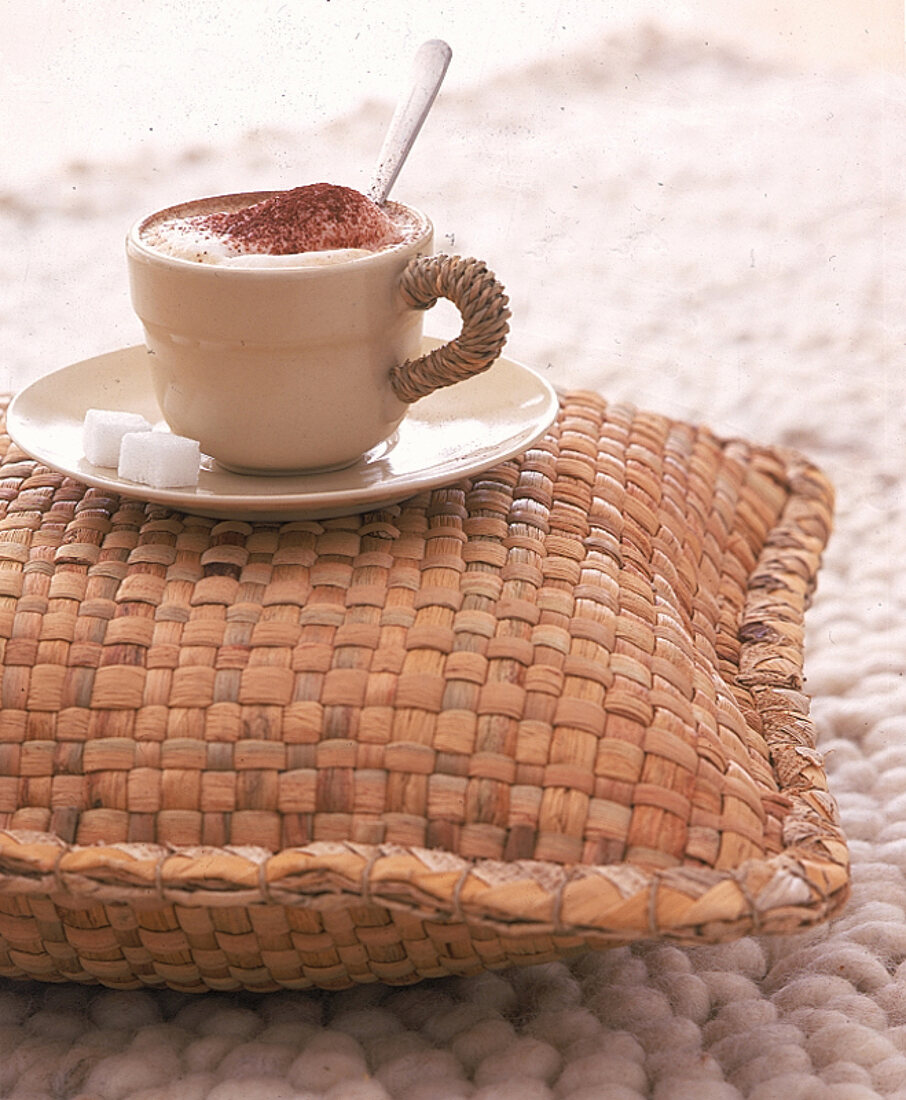 Eine Tasse Cappuccino steht auf einem Kissen aus Seegras