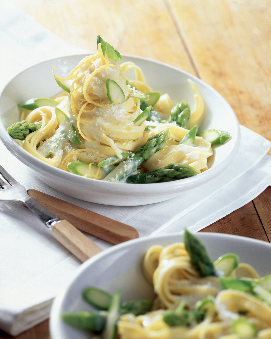 Tagliatelle pasta with green asparagus, lemon and cream sauce in white bowl