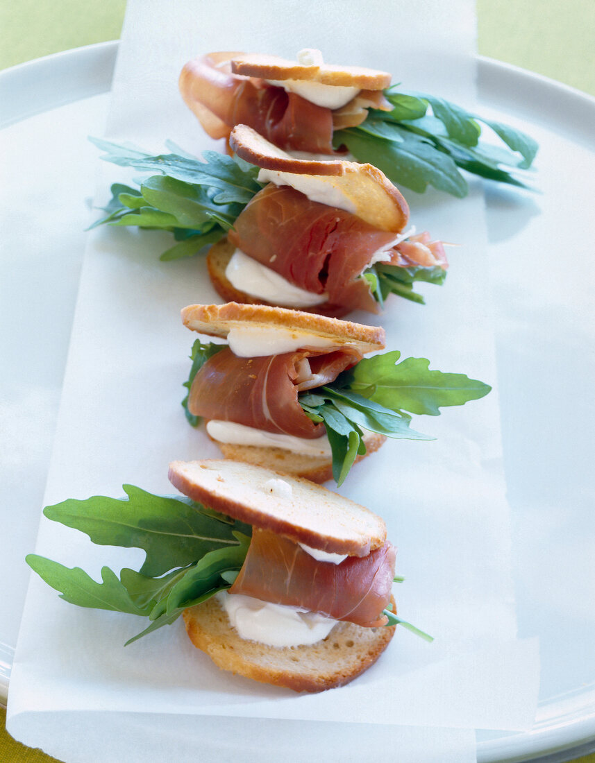 Canapes with ham and arugula on plate