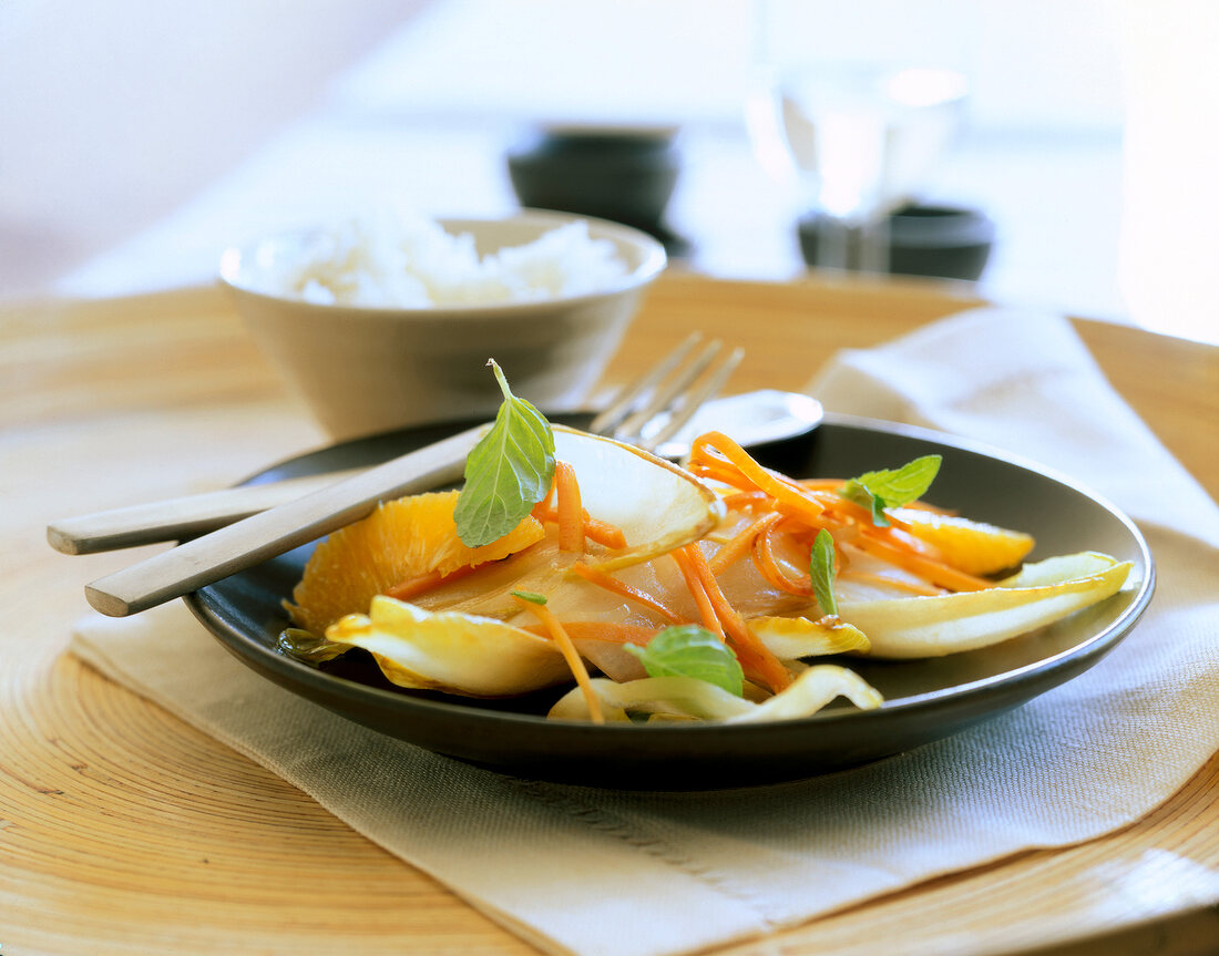 Caramelised chicory dish with carrot strips, oranges and mint on plate