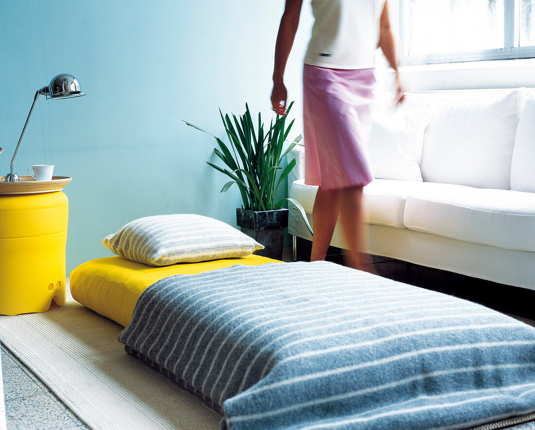 Woman walking beside guest bed and white sofa