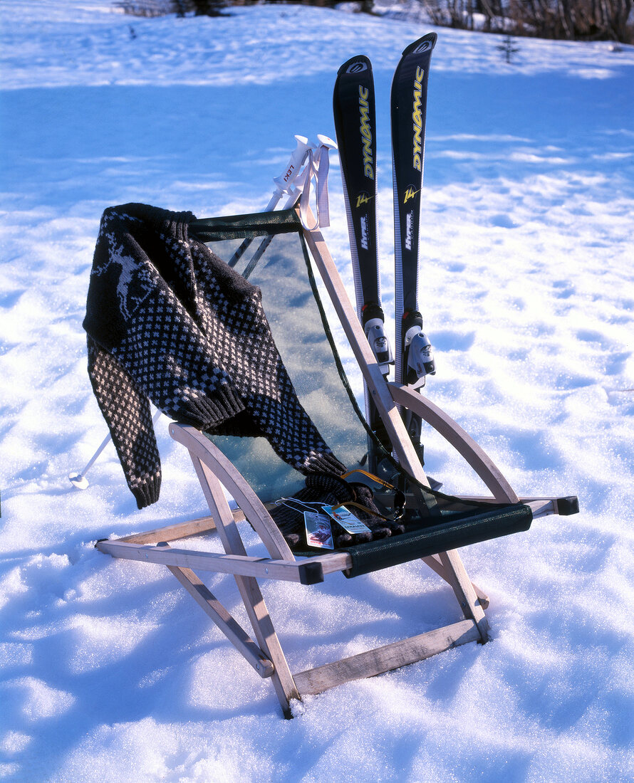 Liegestuhl mit Sonnenbrille,Handschu he und Pullover im Schnee.X