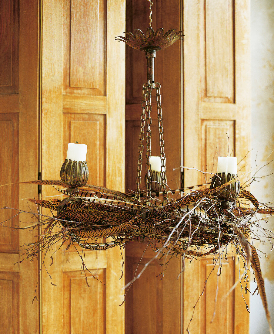 Close-up of chandelier with candles, pheasant feathers and jewellery wreath