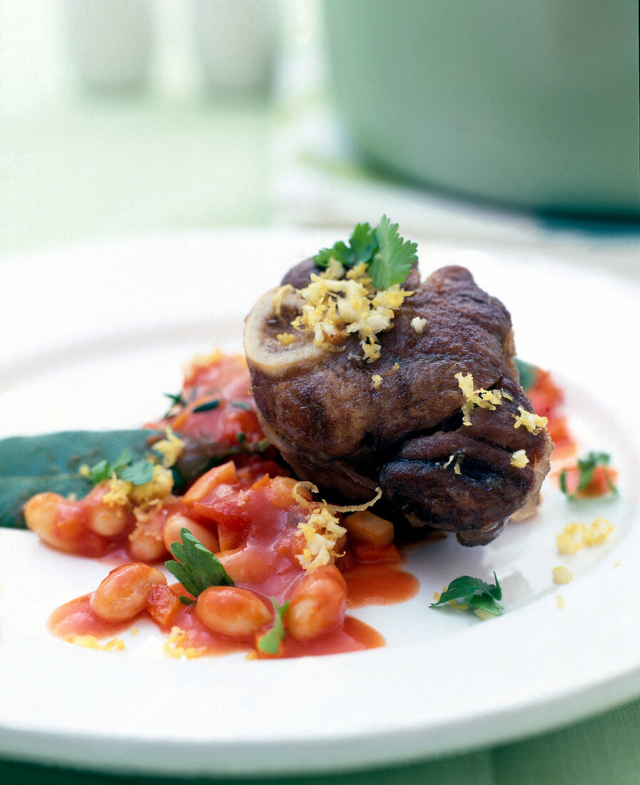 Close-up of osso buco with beans and coriander on plate