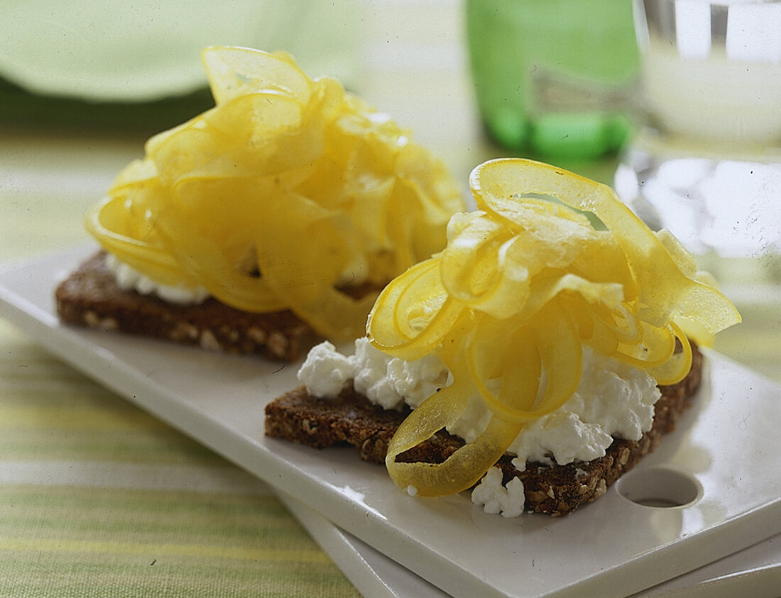 2 Schwarzbrote mit Frischkäse und dünne gelbe Paprikastreifen