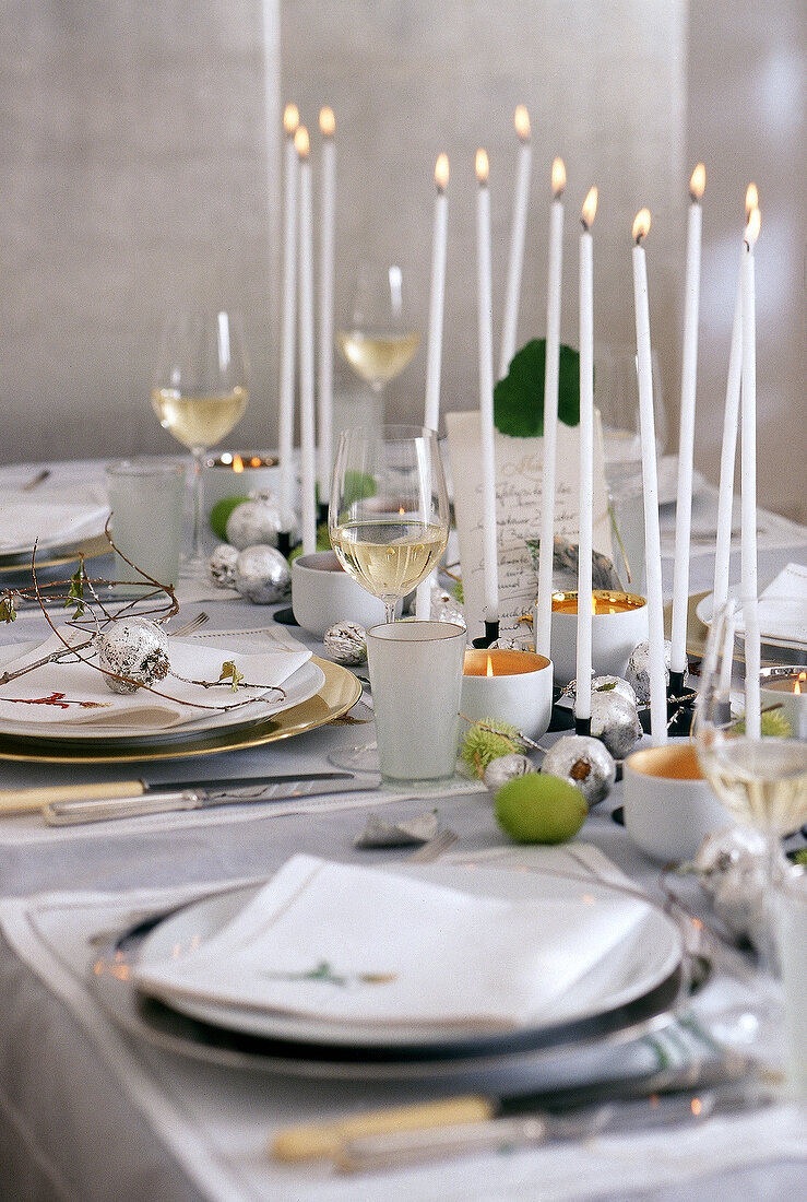 Festlicher Tisch mit vielen Kerzen, versilberten Nüssen und Granatäpfeln