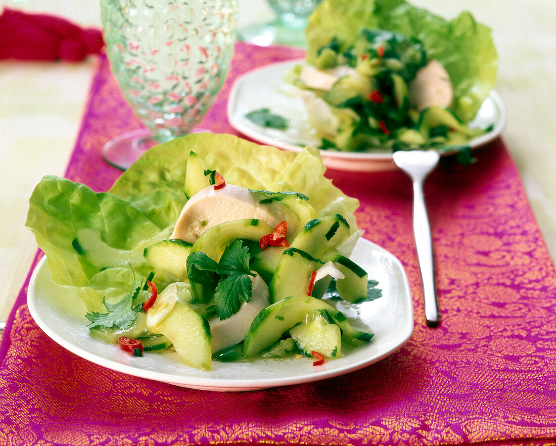 Salad with chicken strips, cucumber, red pepper, salad leaves and lime sauce on plate