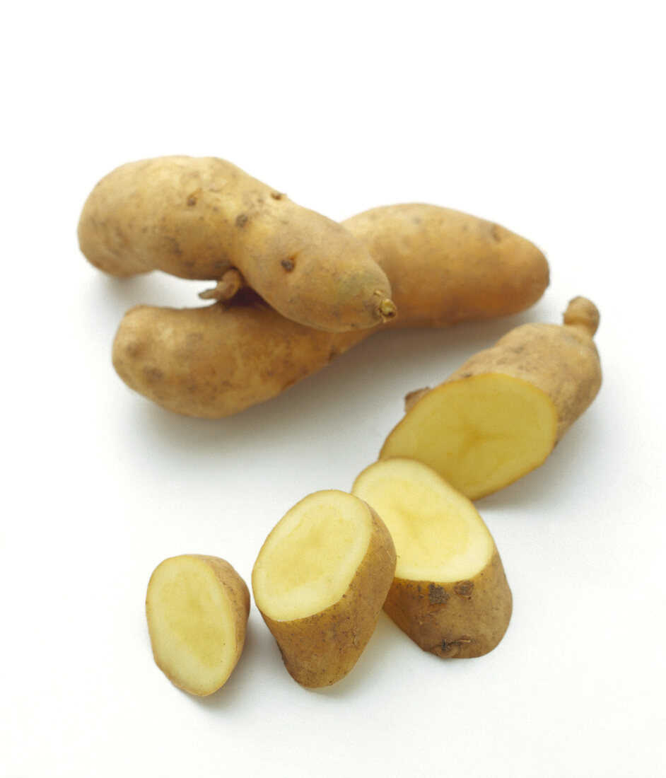 Two whole and one sliced bamberger potato on white background