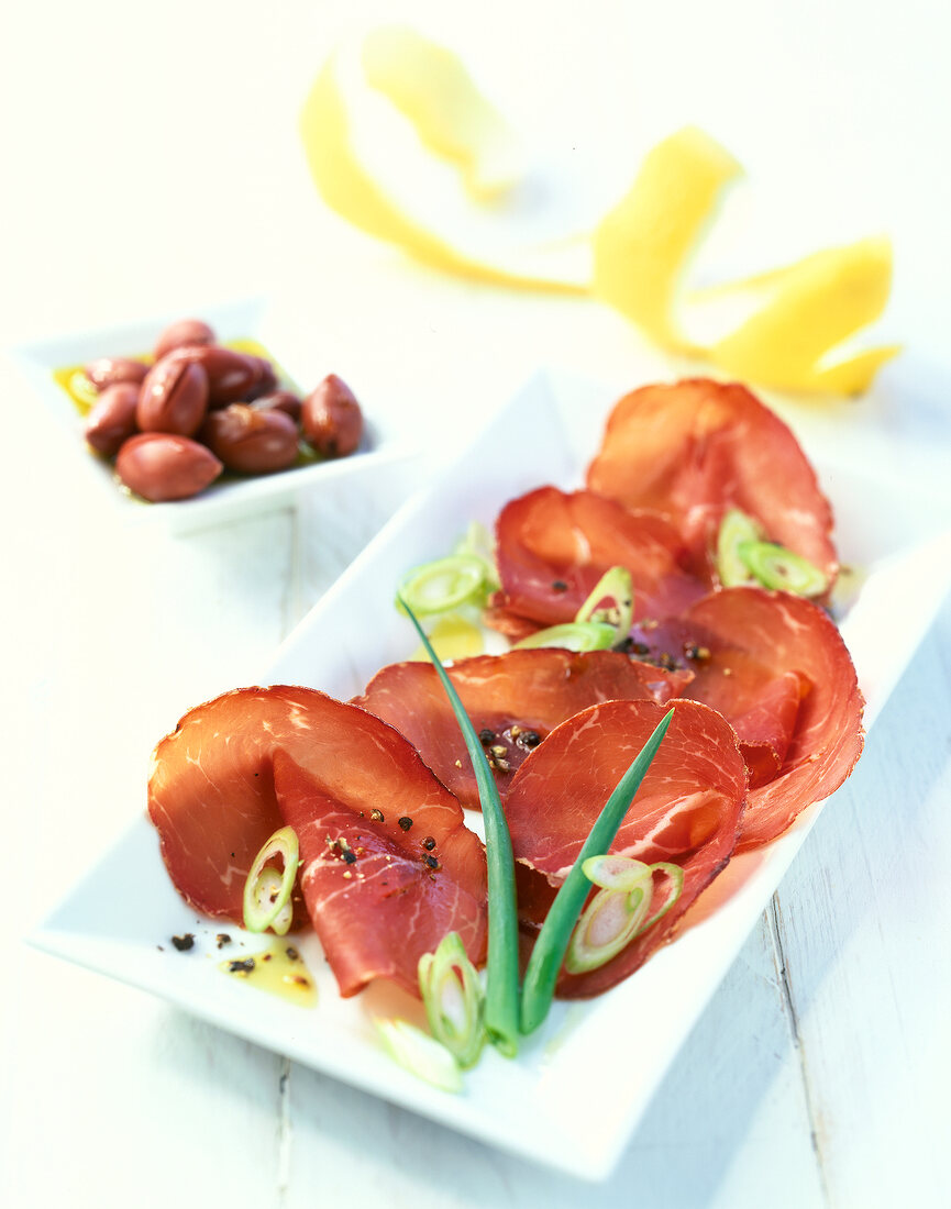 Carpaccio of beef with spring onions on white plate