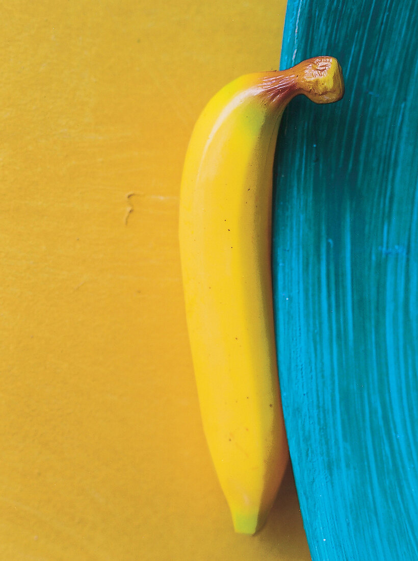 Künstliche Banane an blauem Tellerrand