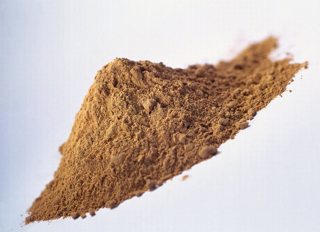 Heap of brown volcanic healing clay on white background