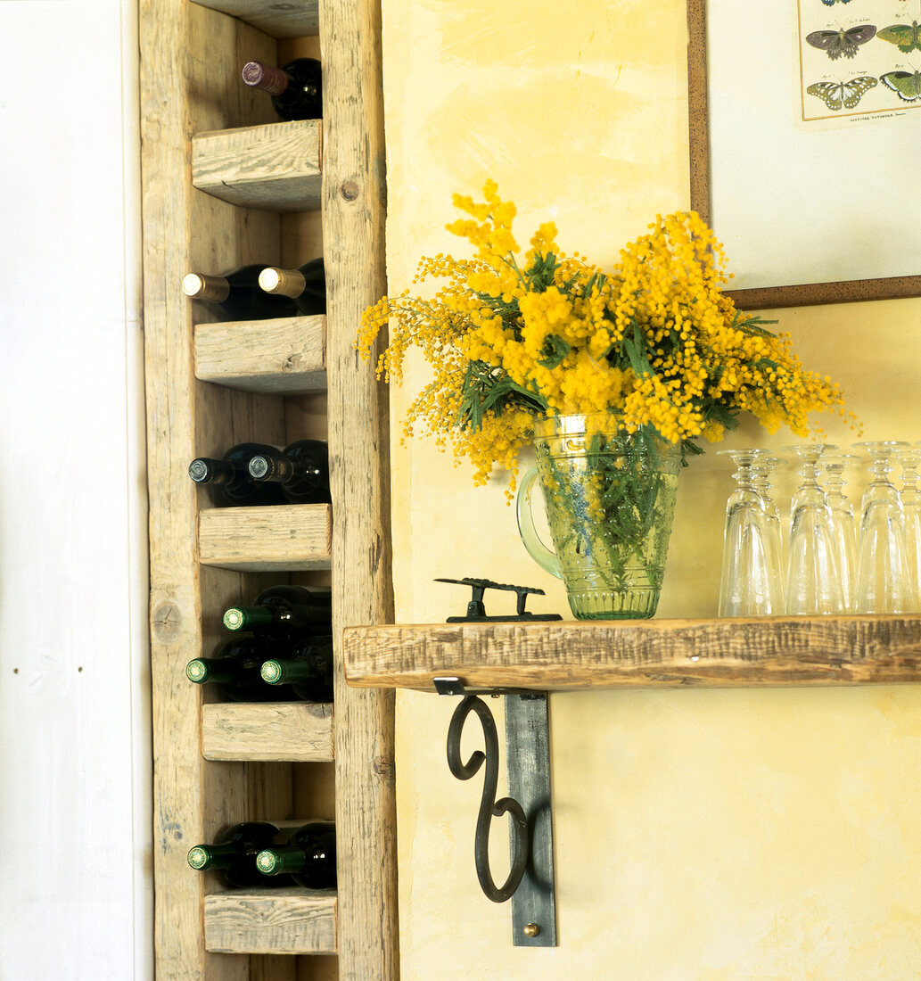 Inset in wall with wine bottles and a wooden board with flowers in glass vase and glasses