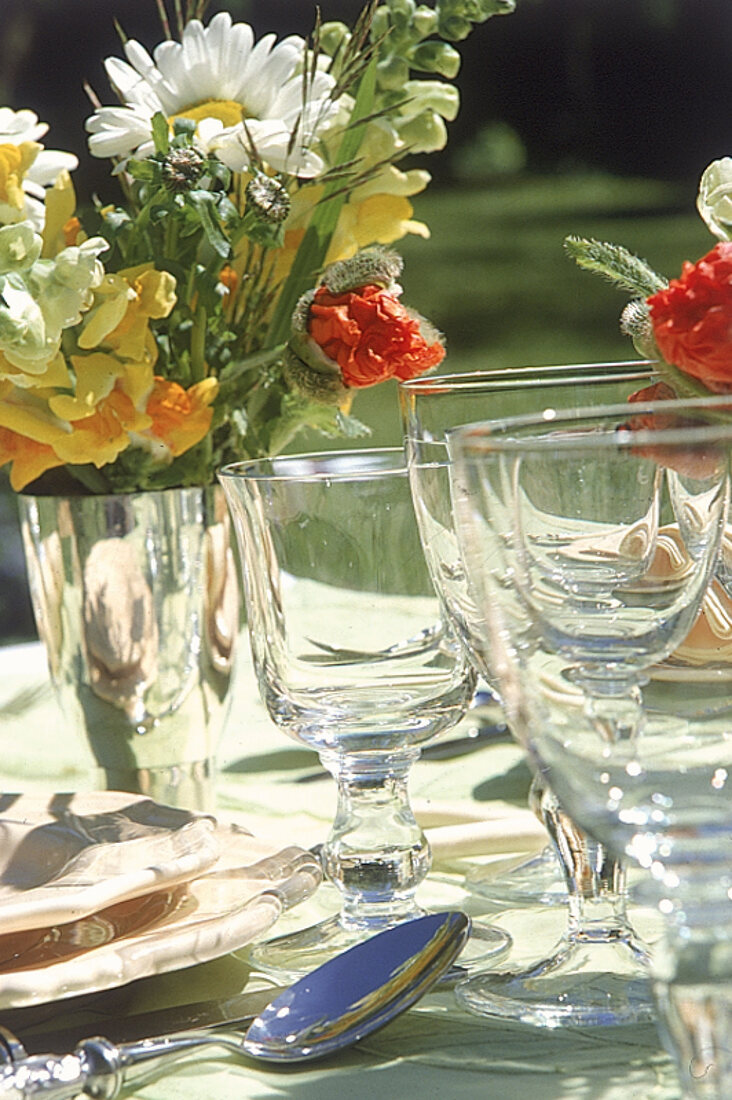 Gläser auf einem gedecktem Tisch,von denen eines mit Blumen gefüllt ist