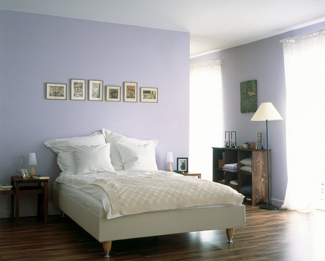 View of bedroom with purple walls, white bed and wooden furniture
