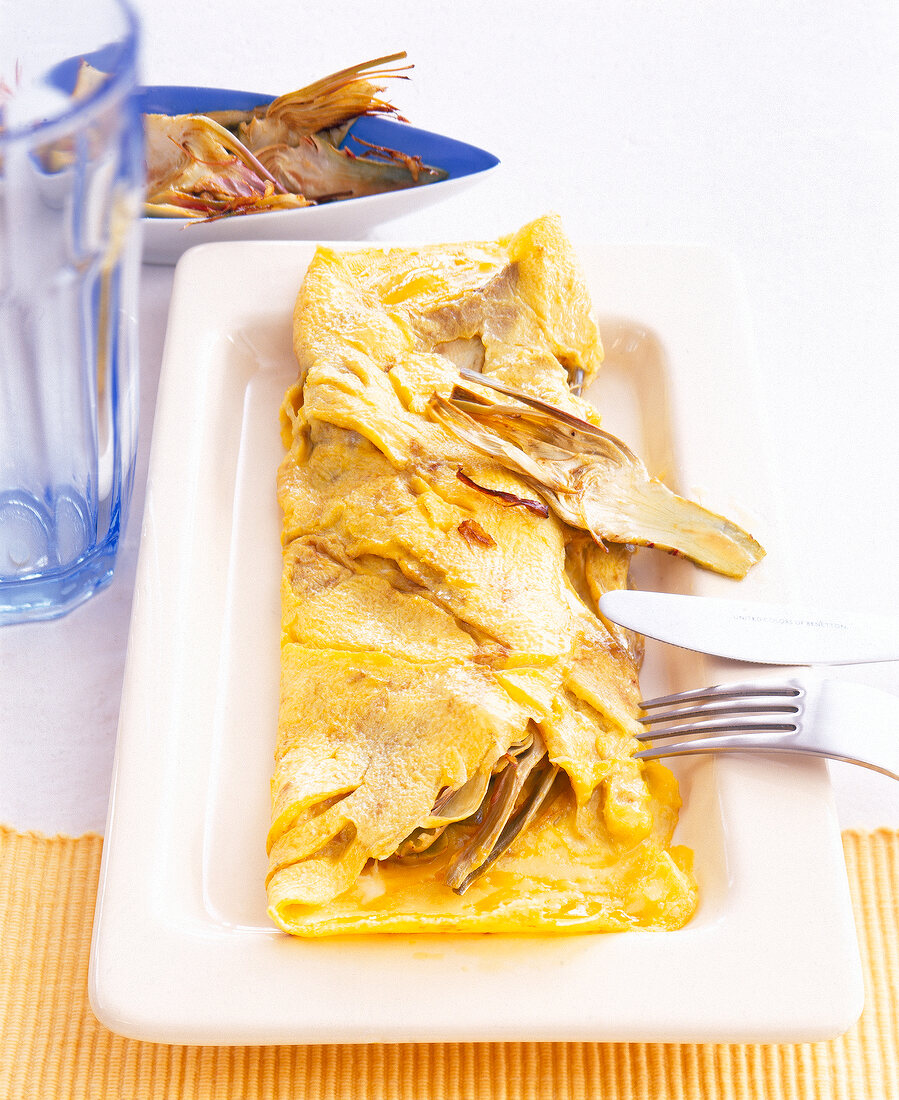 Omelette with fried lemons and artichokes on rectangular plate