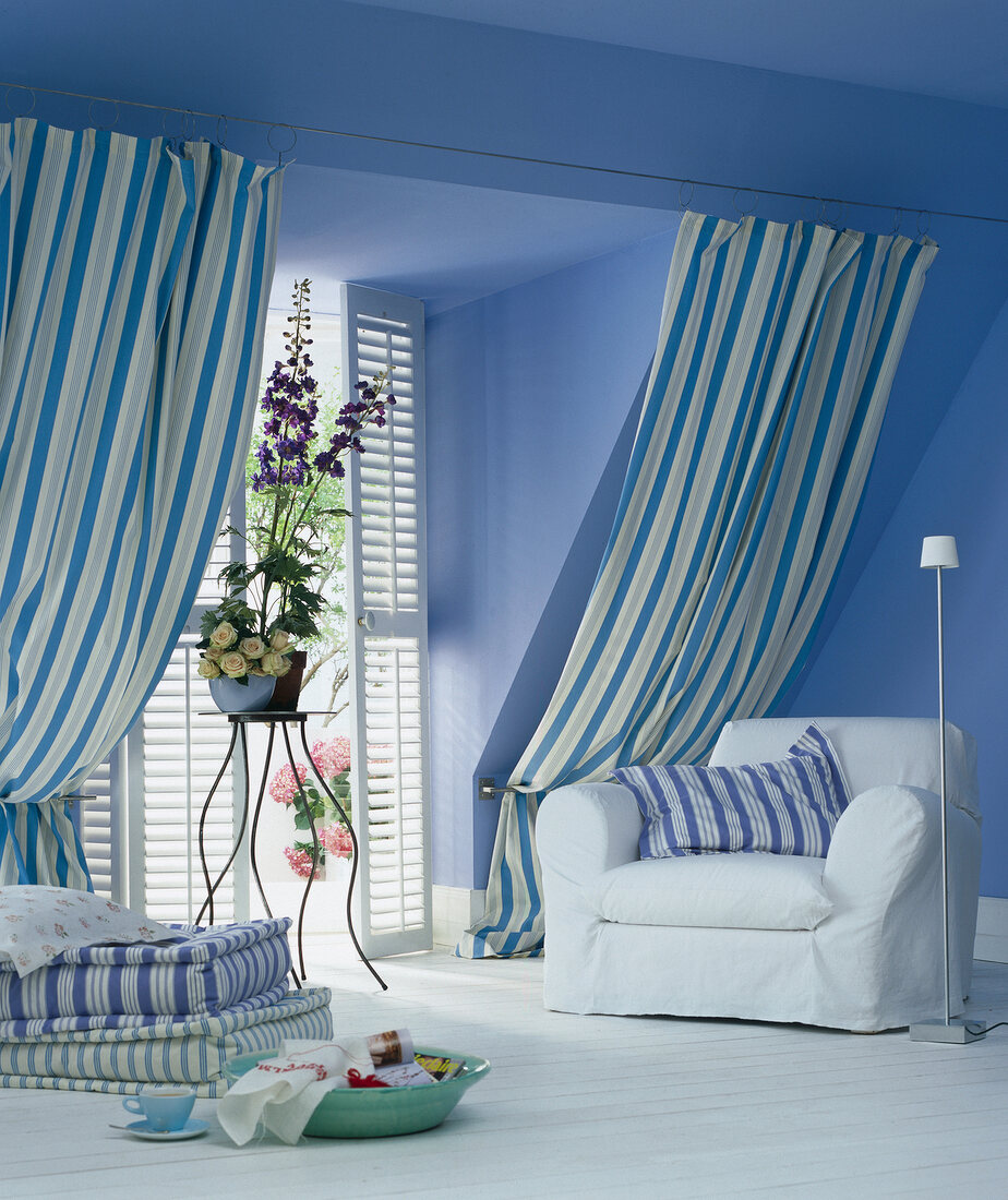 View of dormer window with slatted door, flower vase, armchair and striped curtains