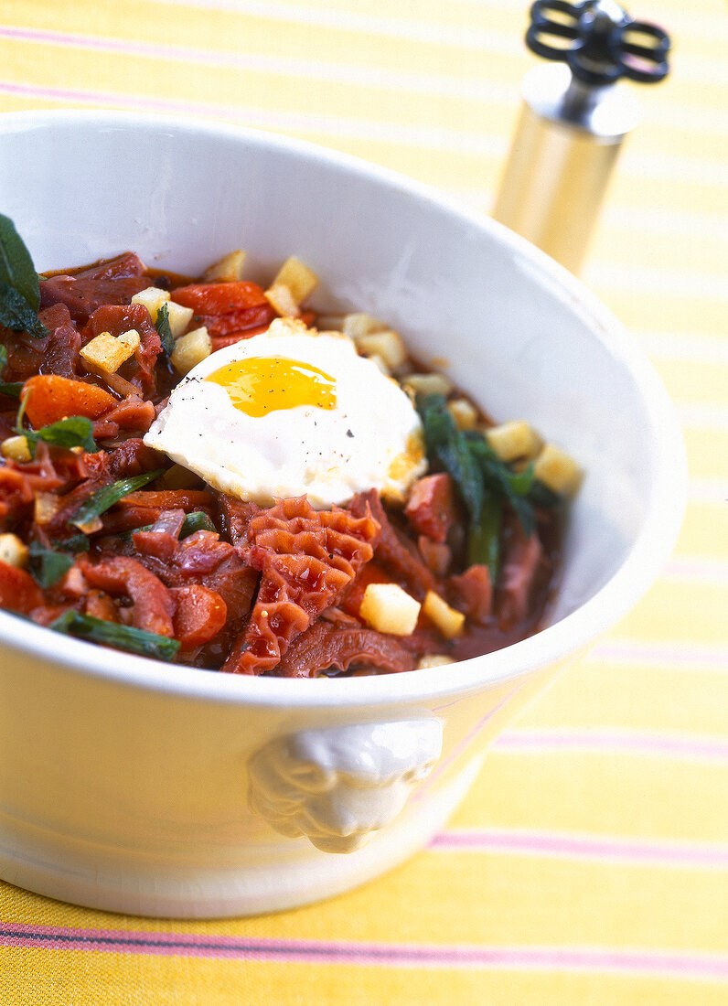 Close-up of tripe with pickled vegetables and fried egg in serving bowl