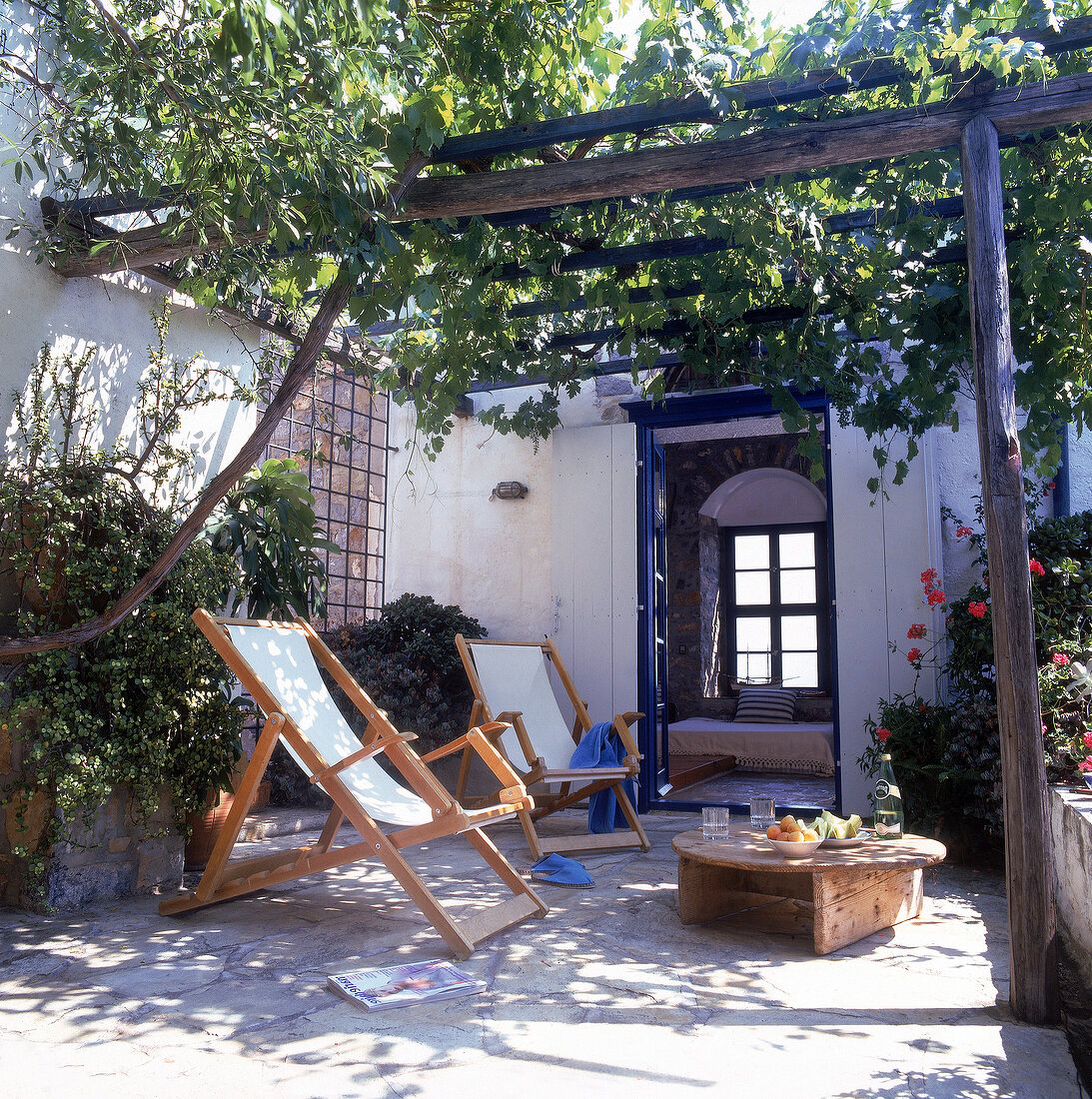 2 Liegestühle auf der Terrasse unter einer weinberankten Pergola