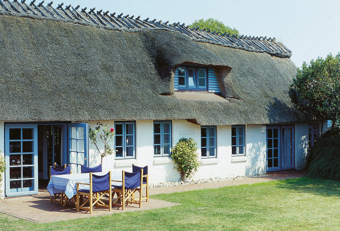 Reetdachkate mit blauen Fensterrahmen,Terrasse m. Gartenmöbeln