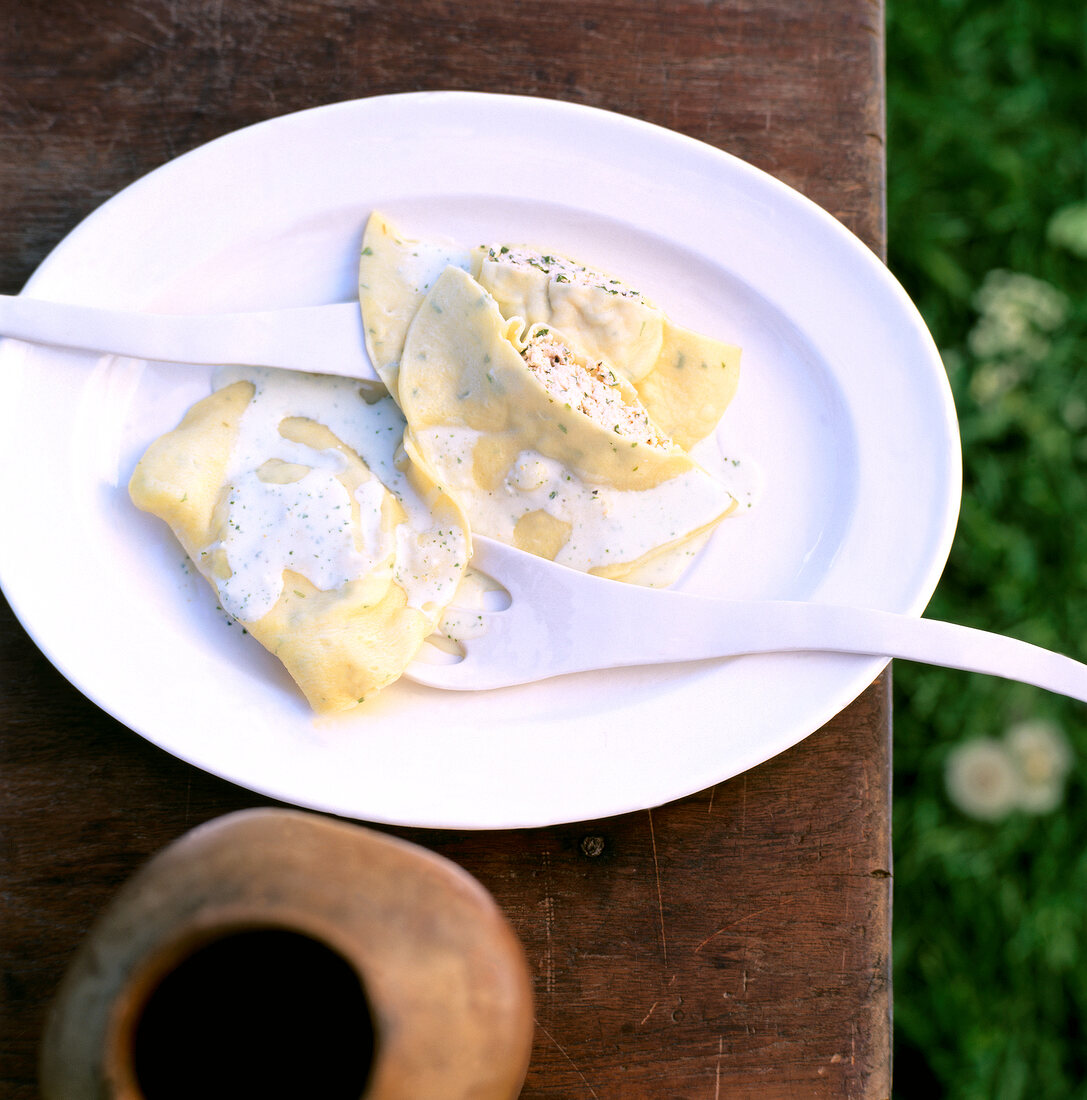 Close-up of herb ravioli with salmon and goat cheese on white plate