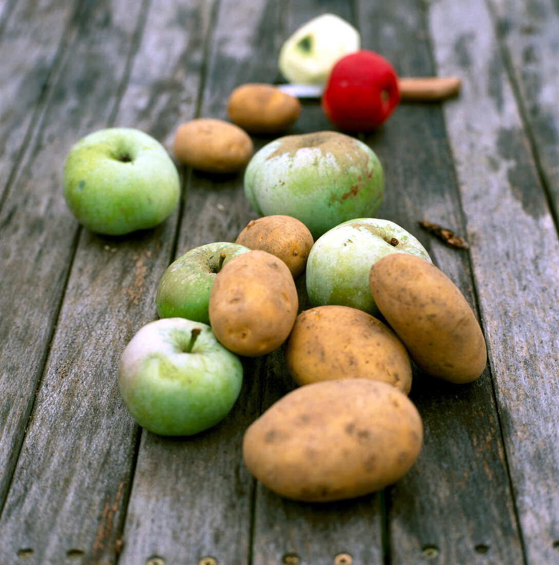 Äpfel und Kartoffeln liegen auf einem Holztisch