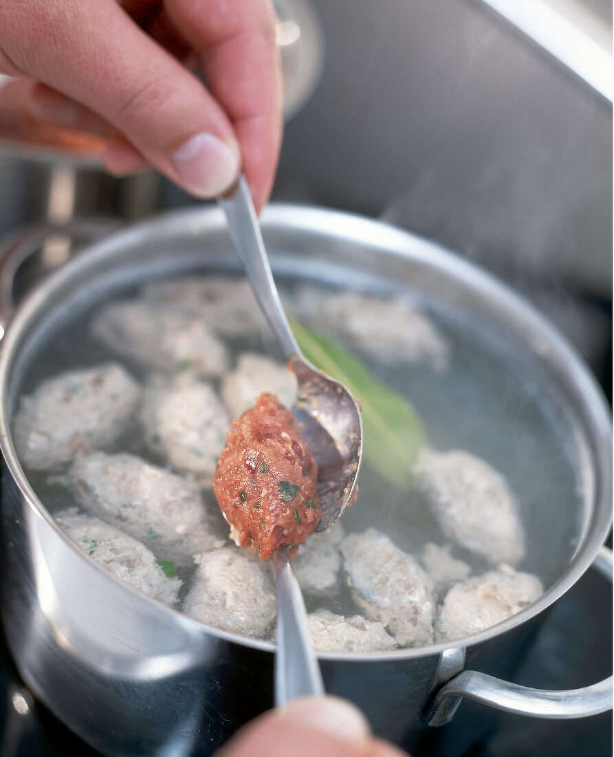 Close-up of liver dumplings being placed in boiling salted water