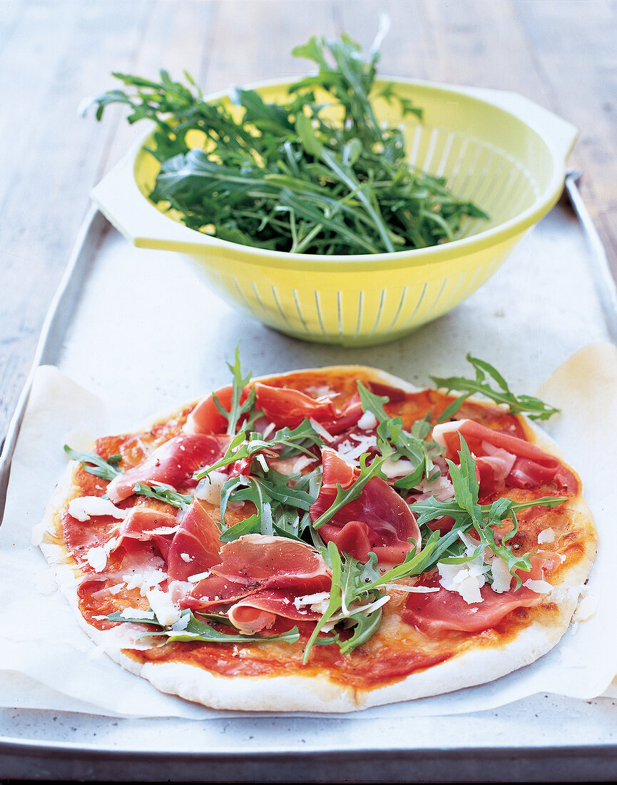 Ein kleine Pizza mit rohem Schinken, Rucola und Parmesan