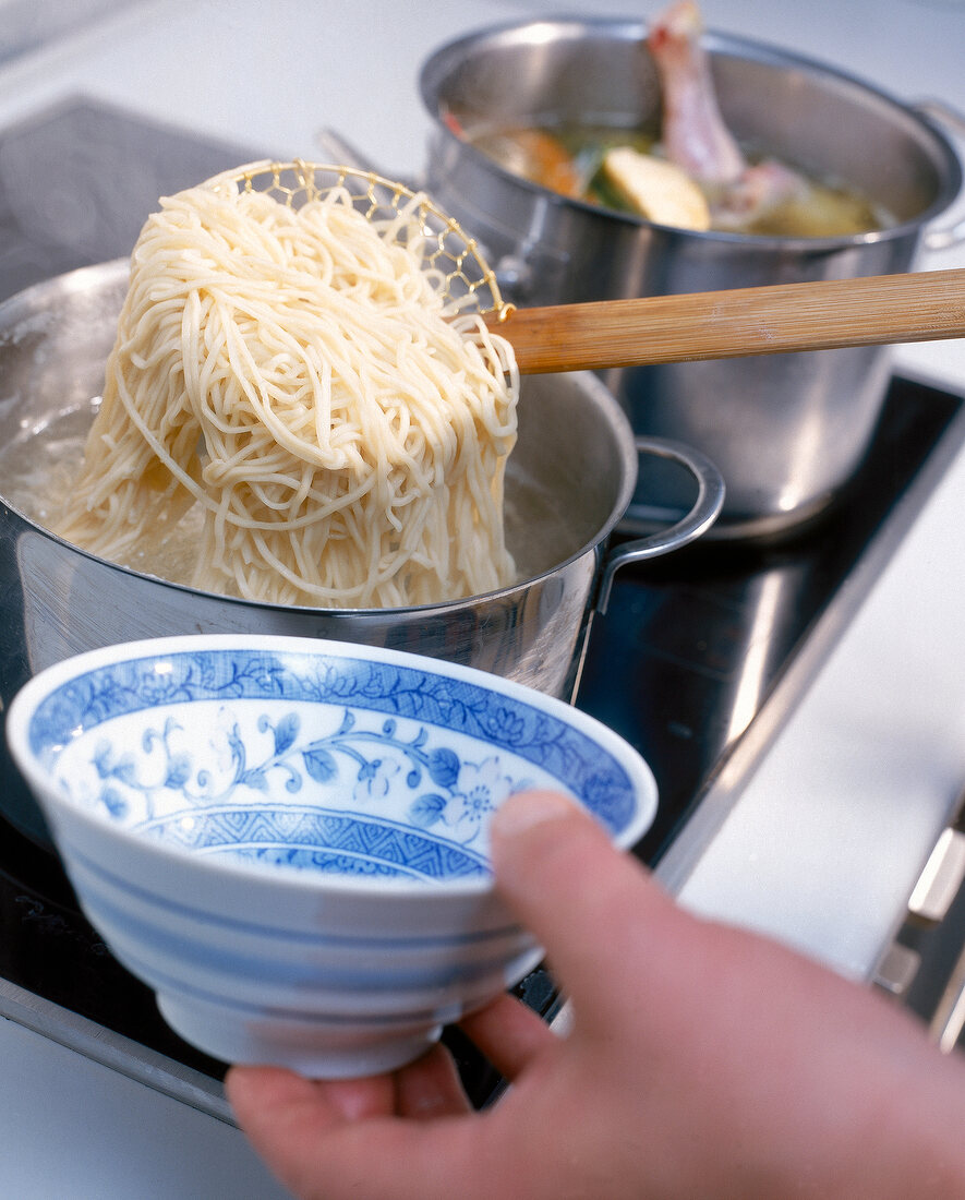 Close-up of boiled noodles being fetched with a ladle from pot