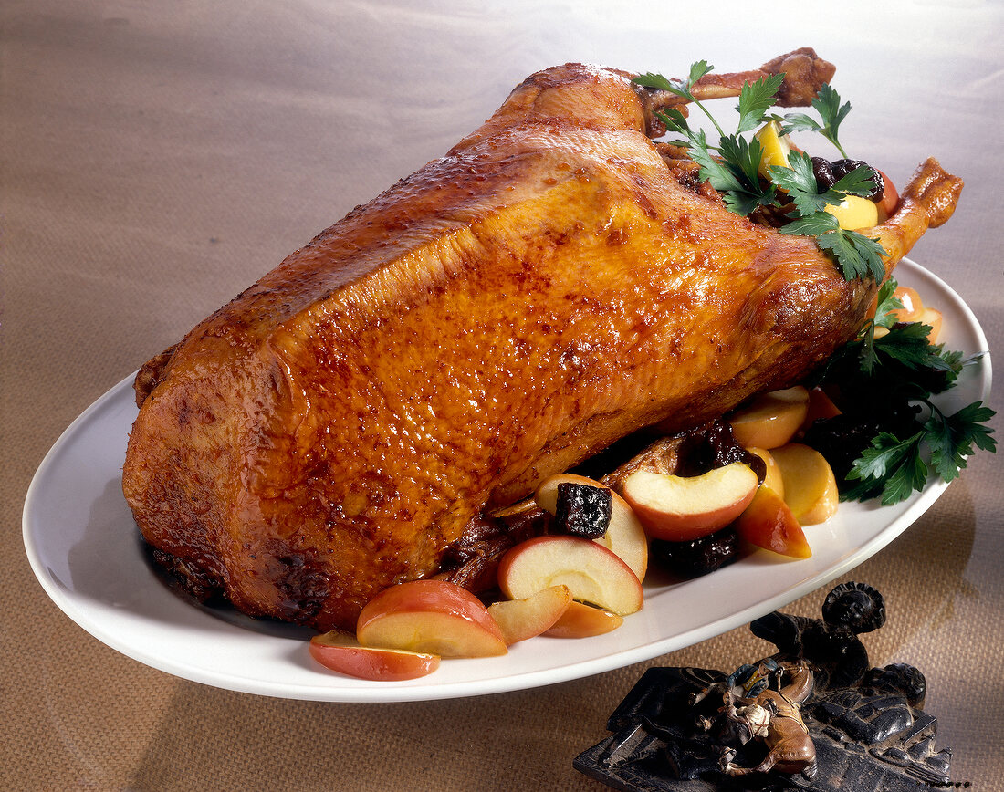 Roasted goose with apples and prunes on serving dish