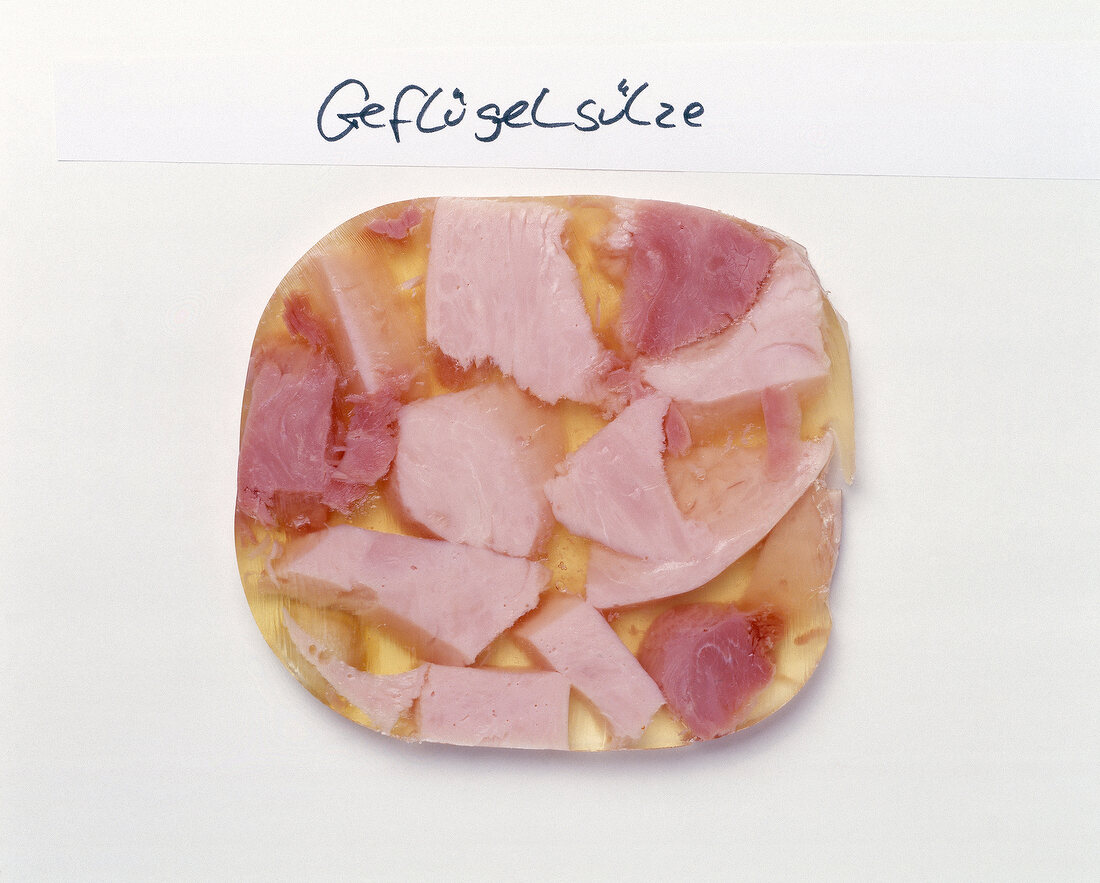 Close-up of chopped poultry meat in jelly on white background